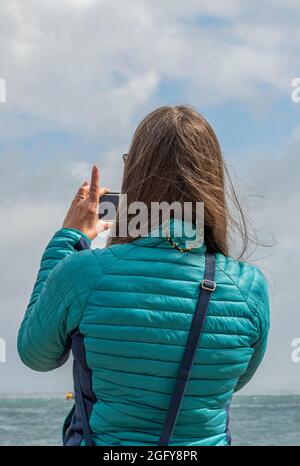 giovane donna fotografa con smartphone, femmina che usa il telefono per scattare una foto, signora che scatta una foto con uno smartphone moderno, foto del telefono. Foto Stock