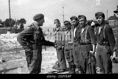 La liberazione di Honfleur, Normandia, Francia durante la seconda guerra mondiale. 26 agosto 1944. Belgio il soldato di Iron Brigade cerca giovani soldati tedeschi dopo la loro resa. Foto Stock