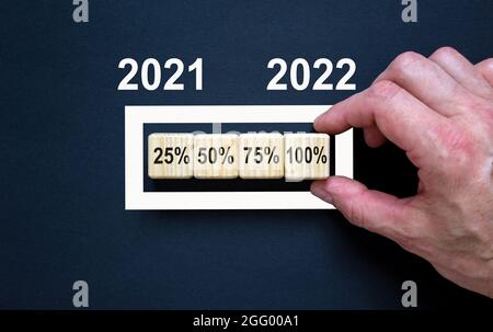 2022 felice anno nuovo simbolo. I cubi di legno simboleggiano il cambiamento del nuovo anno 2022. Businessman mano, numeri 2021, 2022. Bellissimo sfondo nero. Foto Stock