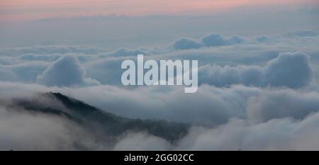 Vista aerea delle nuvole sparare sopra il cumulo dalla cima della montagna Foto Stock