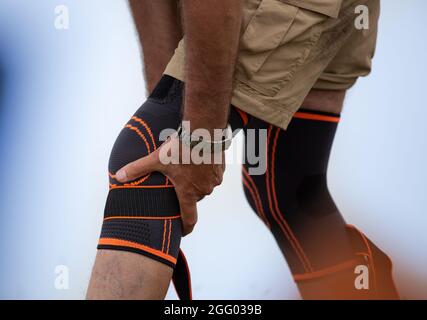 Hiker che mette il ginocchio brace su. Gamba ferita e concetto di sicurezza nel tempo libero Foto Stock