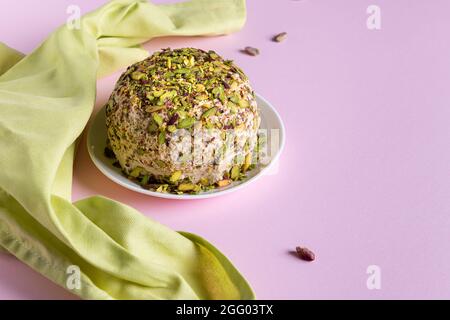 Halva al sesamo con pistacchi, poche noci sparse e tovagliolo di lino verde su carta rosa. Orientamento orizzontale. Spazio di copia. Tradizionale medio Oriente Foto Stock
