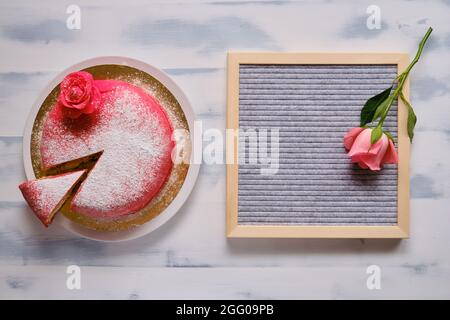 Torta rossa ricoperta di marzapane con fiore e cosparso di zucchero bianco in polvere. Sfondo per spazio di copia Foto Stock