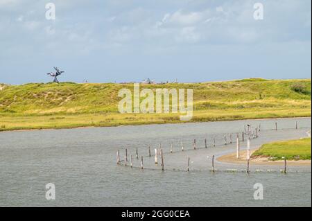 Knokke-Heist, Fiandre, Belgio - 6 agosto 2021: Riserva naturale di Zwin. Qualcuno siede sulla statua di Keun nelle dune che separano il Mare del Nord da Zwin sotto il blu c Foto Stock