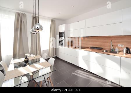 bella luce bianca fresca cucina ampia aperto grande interno in legno lampada color argento su tavolo da pranzo Foto Stock