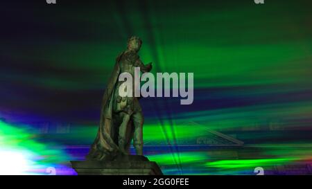 Greenwich, Londra, Regno Unito. 27 ago 2021. La Statua del Re Giorgio II si erge circondata dalle illuminazioni luminose. Nella sua serata ufficiale di lancio pubblico, 'Borealis' di Dan Archer illumina i cieli sopra l'Old Royal Naval College nel Royal Borough di Greenwich. 'Borealis' è una riproduzione ipnotizzante dell'aurora boreale nel cielo. Fa parte dell'annuale Greenwich and Docklands Festival, che si terrà dal 27 agosto all'11 settembre 2021. Credit: Imagplotter/Alamy Live News Foto Stock