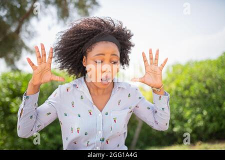Giovane donna scioccata che guarda giù con un'espressione sorpresa sul suo volto. Foto Stock