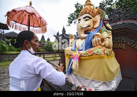 Palu, Indonesia. 28 agosto 2021. Gli Indù fanno offerte alla statua di Ganesha durante il culto di Saraswati durante la pandemia di Covid-19 alla pura Agung Wana Kerta Jagatnatha, Palu City, nella Provincia Centrale di Sulawesi. Saraswati Day per gli Indù si ritiene sia il giorno della discesa della conoscenza. Gli indù che vengono a adorare sono limitati dovuto l'aumento dei casi di Covid-19 mentre mantengono i protocolli di salute rigorosi. (Foto di Adi Pranata/Pacific Press) Credit: Pacific Press Media Production Corp./Alamy Live News Foto Stock