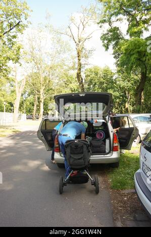 POZNAN, POLONIA - 11 giu 2016: Un uomo che carica un buggy bambino in un'auto al parcheggio di Park Cytadela, Poznan, Polonia Foto Stock