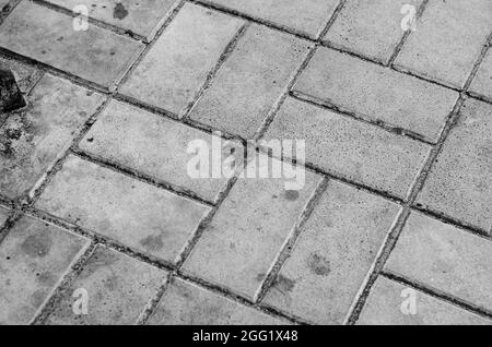 Marciapiede sporco ricoperto di tegole pentaedriche grigie. Composizione geometrica. Vista dall'alto ad angolo. Messa a fuoco selettiva. Foto Stock