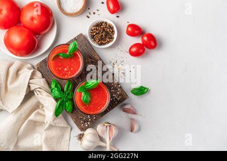 Succo di pomodoro fresco fatto in casa in due bicchieri su sfondo grigio. Vista dall'alto, spazio di copia. Foto Stock