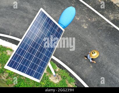 Nanning. 22 luglio 2021. La foto aerea scattata il 22 luglio 2021 mostra un villager che cammina accanto a una lampada solare alimentata da strada nel villaggio Maobishan della Contea autonoma di Gongcheng Yao, nella regione autonoma di Guangxi Zhuang, nella Cina meridionale. Sempre più lampade solari per la strada sono state erette in aree nascoste nelle montagne di Guangxi, illuminando il cielo notturno per le persone che vivono lì. Credit: Yuyuyuyuyuyuyuyuyuyuyuyuyuyuyuy Foto Stock