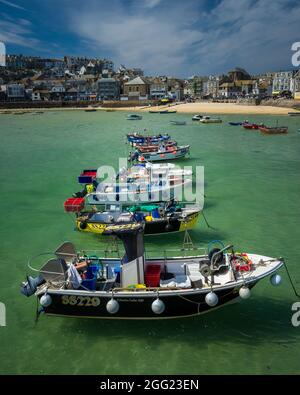 St. Ives Harbour Beach Cornwall - UNA linea di barche galleggianti su belle acque cristalline con pittoresca città alle spalle. Foto Stock