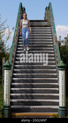 Donna che scende lungo un ponte ferroviario durante il giorno a Bognor Regis. Foto Stock