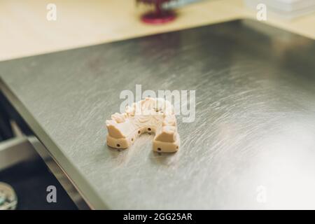 Muffa di una dentiera su un tavolo in acciaio inox in un laboratorio dentale di corone di porcellana Foto Stock