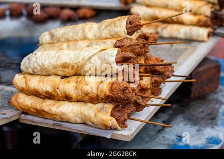 Delizioso cibo fritto di strada seekh kabab su un bordo di legno da vicino Foto Stock