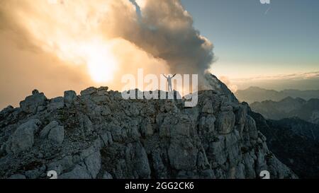 Escursionista avventura uomo di viaggio esploratore escursionista. Piccola silhouette di uomo escursionista che gode di bella alba in montagna mattina. Viaggiatore con mani rialzate Foto Stock