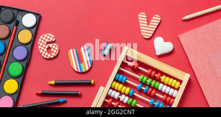 La scuola fornisce la disposizione piatta. Cancelleria su sfondo rosso, vista dall'alto. Istruzione, ritorno a scuola, concetto di creatività dei bambini Foto Stock