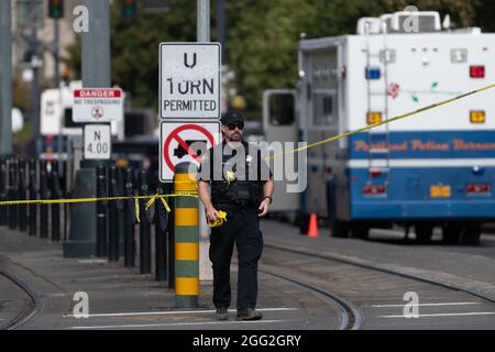 Portland, Stati Uniti. 27 ago 2021. Un ufficiale di polizia di Portland utilizza il nastro della scena del crimine per delimitare un'area di indagine dopo uno sparo mortale che ha lasciato un ufficiale ferito a Portland, Oregon. All'inizio della giornata, il dea ha servito un mandato ad un uomo in un complesso di appartamenti, poco dopo, la polizia di Portland è stata chiamata per il back-up e un sparo seguito, lasciando un ufficiale di polizia di Portland ferito. Il sospetto è stato pronunciato morto sulla scena. Portland, Oregon, USA, 27 agosto 2021 (Mathieu Lewis-Rolland/SIPA USA) Credit: Sipa USA/Alamy Live News Foto Stock