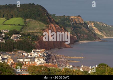 Sidmouth, Devon, Regno Unito. 27 agosto 2021. I membri del pubblico si alzano pericolosamente vicino al bordo di scogliere sbriciolate mentre osservano le frecce rosse della RAF che si esibiscono su Sidmouth, Devon. Le scogliere a Sidmouth sono crollate in questo luogo circa mezza dozzina di volte nelle ultime 4-6 settimane. Credit: Ian Williams/Alamy Live News Foto Stock