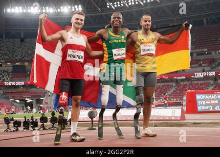 Tokio, Giappone. 28 agosto 2021. Paralimpiadi: Atletica, salto lungo, uomini, finale, allo Stadio Olimpico. I vincitori della medaglia si riuniscono prima della cerimonia di premiazione. La medaglia di bronzo Daniel Wagner dalla Danimarca (l-r), la medaglia d'oro Ntando Mahlingua dal Sudafrica e la medaglia d'argento Leon Schäfer dalla Germania hanno la loro bandiera nazionale nelle loro mani. Credit: Marcus Brandt/dpa/Alamy Live News Foto Stock