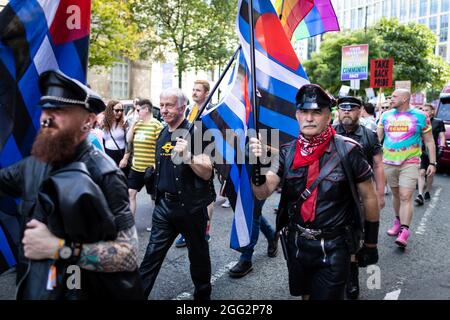 Manchester, Regno Unito. 28 agosto 2021. I manifestanti con bandiere marciano attraverso la città durante una protesta Pride. Centinaia di persone marciano attraverso la città per protestare contro Manchester Pride Ltd. I manifestanti chiedono finanziamenti migliori per le associazioni di beneficenza e i gruppi comunitari LGBTQIA di Manchester. Credit: Andy Barton/Alamy Live News Foto Stock