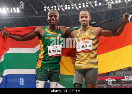 Tokio, Giappone. 28 agosto 2021. Paralimpiadi: Atletica, salto lungo, uomini, finale, allo Stadio Olimpico. Due dei vincitori della medaglia si riuniscono prima della cerimonia di premiazione. Il medaglia d'oro Ntando Mahlingua dal Sudafrica (l) e il medaglia d'argento Leon Schäfer dalla Germania tengono la loro bandiera nazionale nelle loro mani. Credit: Marcus Brandt/dpa/Alamy Live News Foto Stock