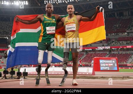 Tokio, Giappone. 28 agosto 2021. Paralimpiadi: Atletica, salto lungo, uomini, finale, allo Stadio Olimpico. Due dei vincitori della medaglia si riuniscono prima della cerimonia di premiazione. Il medaglia d'oro Ntando Mahlingua dal Sudafrica (l) e il medaglia d'argento Leon Schäfer dalla Germania tengono la loro bandiera nazionale nelle loro mani. Credit: Marcus Brandt/dpa/Alamy Live News Foto Stock