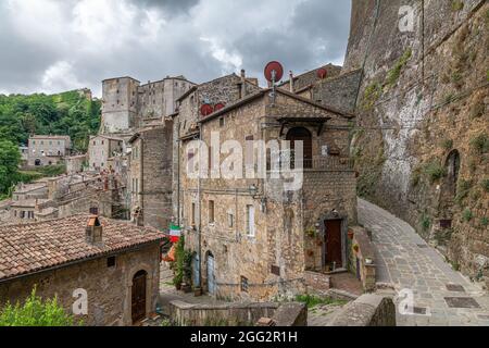 Vista pittoresca di Sorano con scalinata, vicolo, sottopasso e piante nel borgo medievale toscano Foto Stock