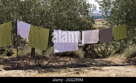 Asciugamani e vestiti appesi ad asciugare nel giardino di una fattoria nella campagna italiana (Toscana, Italia, Europa) Foto Stock