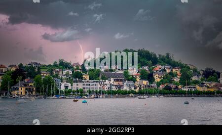 Temporale che sopraggiungono una città sul lago, vista della città e barche nel lago in attesa della tempesta imminente Foto Stock