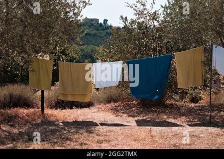 Asciugamani e vestiti appesi ad asciugare nel giardino di una fattoria nella campagna italiana (Toscana, Italia, Europa) Foto Stock