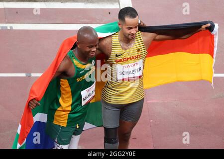 Tokio, Giappone. 28 agosto 2021. Paralimpiadi: Atletica, salto lungo, uomini, finale, allo Stadio Olimpico. Due dei vincitori della medaglia si riuniscono prima della cerimonia di premiazione. Il medaglia d'oro Ntando Mahlingua dal Sudafrica (l) e il medaglia d'argento Leon Schäfer dalla Germania tengono le loro bandiere nazionali nelle loro mani. Credit: Karl-Josef Hildenbrand/dpa/Alamy Live News Foto Stock