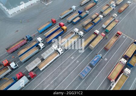 Trasporto merci. Molti autocarri sono in attesa in linea per lo scarico nel porto, vista dall'alto da un quadricottero su autocarri carichi di granella. Concep Foto Stock