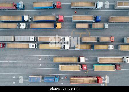 Molti autocarri sono in attesa in linea per lo scarico nel porto, vista dall'alto da un quadricottero su autocarri carichi di granella. Concetto per logistica e fr Foto Stock