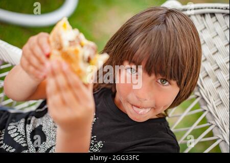 Festa alla griglia con barbecue. Ragazzo felice che ama il barbecue all'aperto. Cibo, persone e concetto di tempo di famiglia Foto Stock