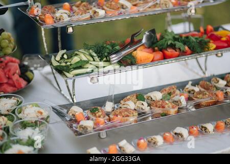Cetrioli e pomodori serviti al tavolo sulla terrazza estiva nel ristorante. Concetto di cibo. Diversi tipi di cibo e bevande sul tavolo Foto Stock