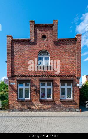 Hel, Polonia - 08.01.2021: Colpo verticale dell'esterno tradizionale, vecchio, mattone rosso, edificio solitario a due magazzini nel porto di Hel in un'estate soleggiata Foto Stock