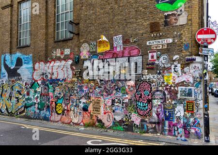 AREA ARTISTICA E CULTURALE DI LONDRA INTORNO A UNA CORSIA DI MATTONI CON DESIGN E SLOGAN CREATIVI A BUXTON STREET Foto Stock