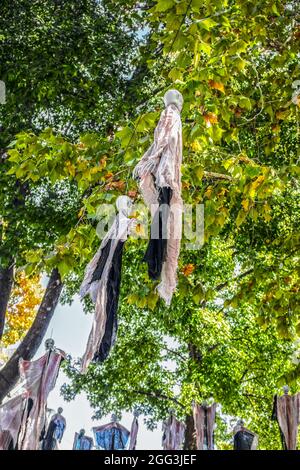 Decorazioni zombie di Halloween appese agli alberi su una strada residenziale americana Foto Stock