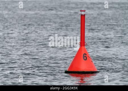 Gallo d'acqua rossa con il numero 6 che galleggia nel Mar Baltico vicino a Hel, Polonia, in una giornata nuvolosa. Foto Stock