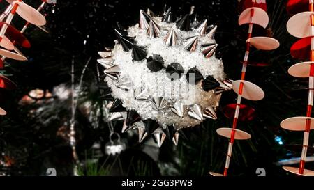 Strano ornamento nero e argento a guglie su albero di Natale tra le altre decorazioni non tradizionali Foto Stock