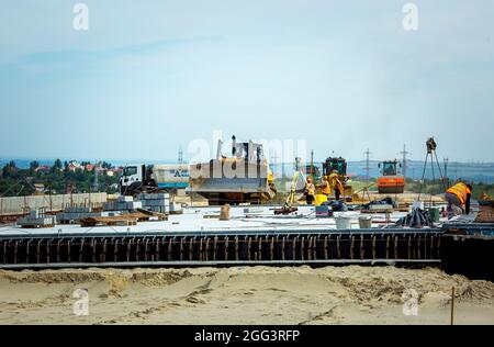 Dnepropetrovsk, Ucraina - 17.08.2021: Costruzione di una nuova tangenziale intorno alla città. Attrezzature da costruzione e lavoratori in loco. Foto Stock