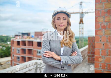 Tranquilla signora sicura di mezza età in piedi sul sito dell'edificio Foto Stock