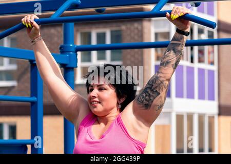 la giovane donna esegue esercizi all'aperto utilizzando la barra orizzontale di strada Foto Stock