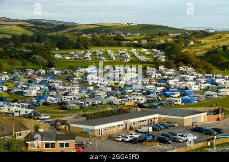 Burton Bradstock, Dorset, Regno Unito. 28 agosto 2021. Meteo Regno Unito. Il campo da campeggio del Freshwater Beach Holiday Park di Burton Bradstock nel Dorset è pieno di roulotte, tende e camper per i turisti in una calda serata di sole durante il fine settimana delle festività. Picture Credit: Graham Hunt/Alamy Live News Foto Stock