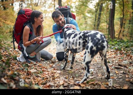 Coppia escursionisti in amore coccolare il loro cane a sentiero escursionistico Foto Stock