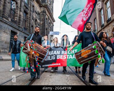 Amsterdam, Paesi Bassi. 28 agosto 2021. I manifestanti hanno una bandiera durante la manifestazione.migliaia di persone si sono radunate nel centro di Amsterdam per dimostrare il loro sostegno al popolo afghano intrappolato a Kabul sotto il regime dei talebani e per esortare il governo olandese a dichiarare l'Afghanistan un paese di origine non sicuro in modo che i rifugiati afghani e afghani non siano documentati i cittadini possono avere il diritto legale di asilo e di sicurezza. (Foto di Ana Fernandez/SOPA Images/Sipa USA) Credit: Sipa USA/Alamy Live News Foto Stock