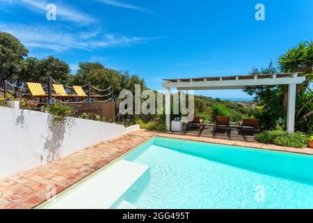 Gazebo nel giardino vicino alla piscina con vista sulla pineta, un luogo per il relax dei turisti. Lettini per prendere il sole. Foto Stock