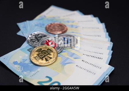 Bitcoins di vari colori su banconote da 20 euro. Bitcoins su venti banconote in euro su sfondo scuro. Concetto di criptovaluta, bitcoin e. Foto Stock